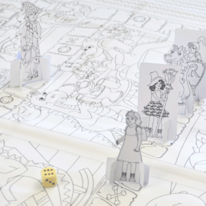 Die ausgeschnittenen Spielfiguren und ein Würfel liegen auf dem Riesenspielmalbuch